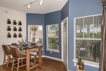 A dining room with a table set for two and a view of the backyard.